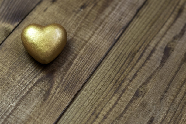 木制背景上的金色心形图案。平铺，复制空间图片下载