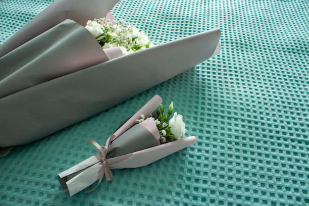 一束小花束和一束大花束，绿松石背景上有玫瑰。一束给妈妈，一束给女儿。母亲节。国际妇女节。节日的概念图片下载