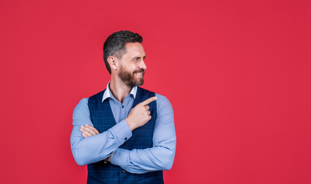 看看这个。快乐男人点食指红色背景。目标指向。手的姿势。营销产品或服务。指示事件或位置的指向方向，复制空间图片下载