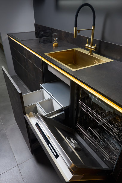 洗碗机和厨余垃圾收纳柜。拉出厨房抽屉，用于垃圾箱，单独的垃圾收集和洗碗机，在金色水槽盆和小面黑色玻璃电动滚刀石器台面下。图片下载