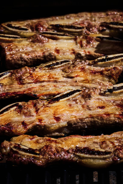 多汁的牛肉排骨和猪排骨在燃气烧烤架上的火上慢慢地烤着图片下载