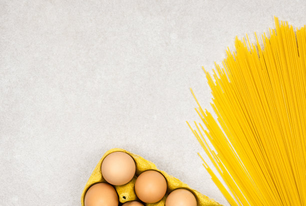 黄色的面条面条与鸡蛋在灰色的背景与复制空间图片下载