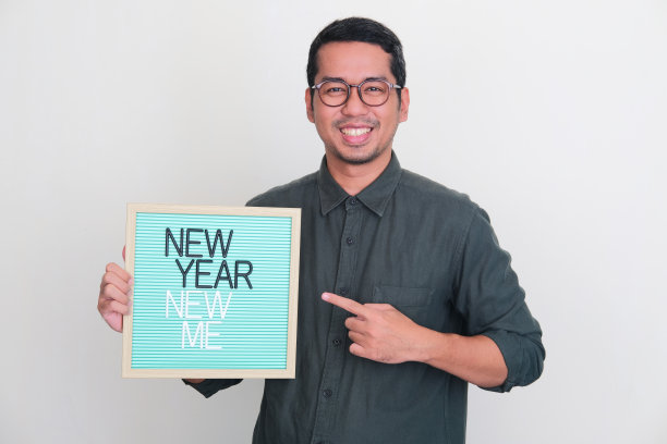 成年亚洲男子抱着木框新年新我的文字图片下载