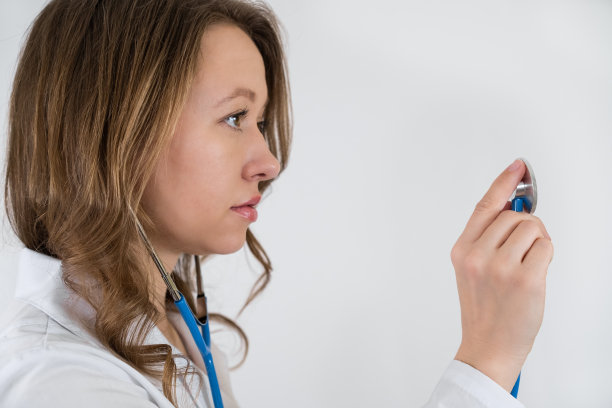 一个穿着晨衣的医生的肖像，手里拿着听诊器。孤立在白色背景中图片下载