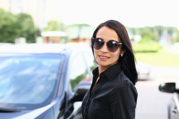 戴墨镜的美女站在一辆车旁边图片下载