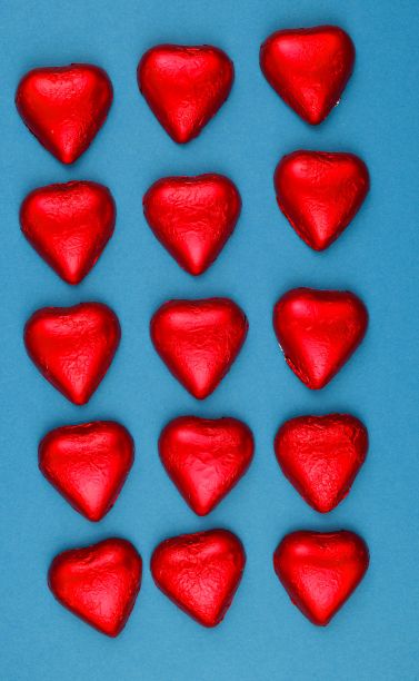 蓝色背景下的红色心形巧克力的垂直镜头——情人节的概念图片下载