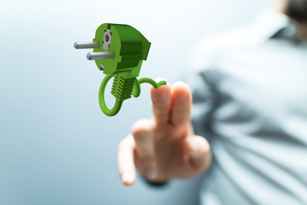 浅聚焦若人手指着一个绿色电源插头图标，安全经济概念图片下载