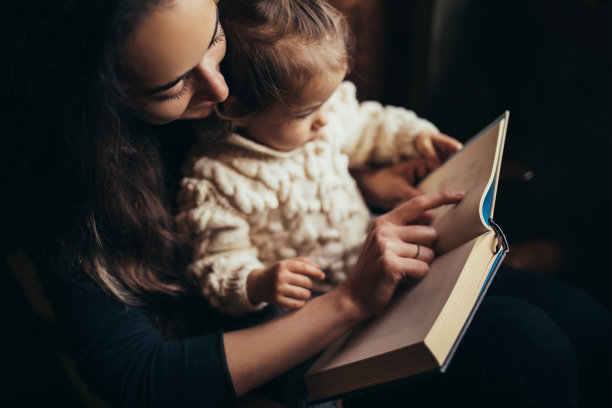 年轻的妈妈和她的小女儿在一起读书。图片下载