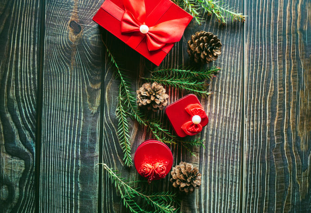 圣诞装饰构图在木制背景与一个美丽的红色礼盒红丝带，树枝，松果图片下载