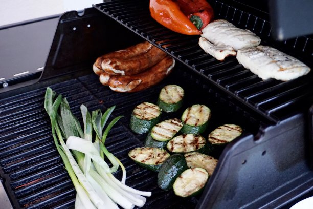 烤蔬菜和香肠。西葫芦，葱花，辣椒粉和烤香肠。鸡肉，香肠和烤蔬菜。晚餐正在烤架上烤着。烤食物。图片下载