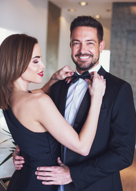 年轻的女人正在为快乐的男人调整领结图片下载