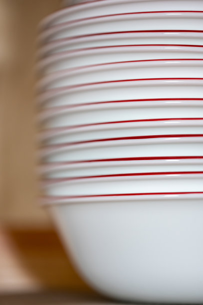 狭窄的景深图片的一个开放的厨房橱柜堆叠陶瓷盘子和碗。图片下载