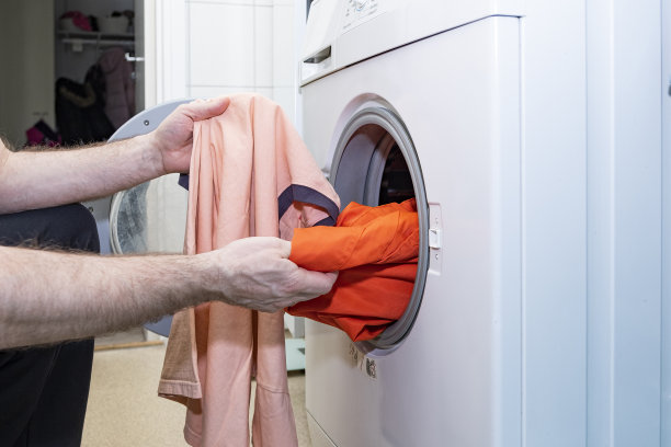 白人男子和有色人种的衣服在洗衣机里，毁了白色的衣服。图片下载