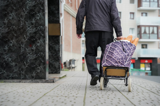 一位老人推着装满面包的购物车走在街上。活跃的老图片下载