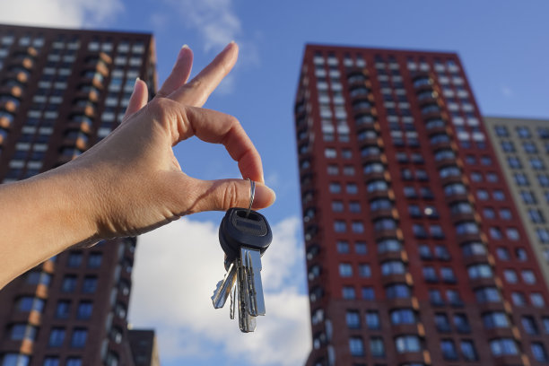 手握钥匙与新型现代住宅建筑，房地产概念图片下载