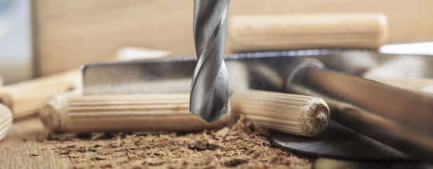 钻头在橡木木板上钻孔，用于木销子。图片下载