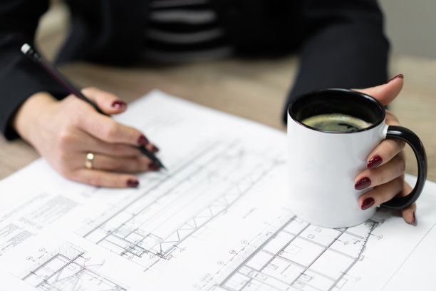 图为，建筑公司的工作人员端着一杯茶观看施工图。图片下载