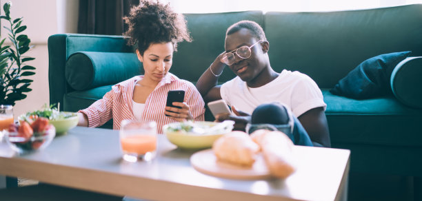 多民族夫妇在家吃饭时使用智能手机图片下载
