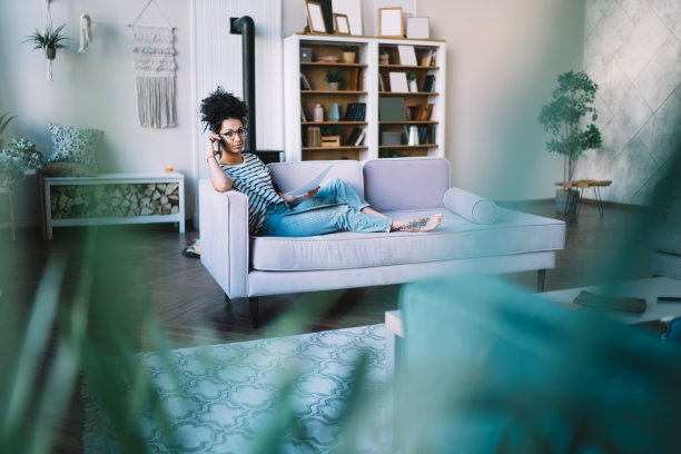 意图黑人妇女在家里沙发上工作时打电话图片下载