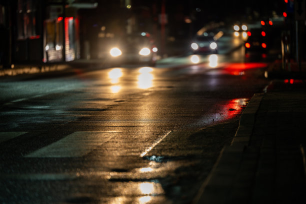城市街道夜晚模糊的背景。接近人行横道的汽车。图片下载