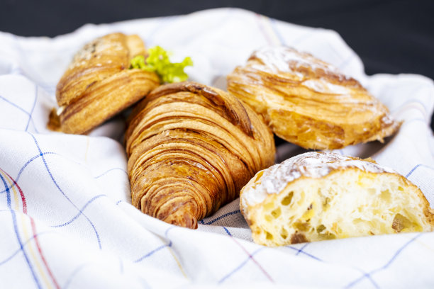 黑色背景的欧式早餐。白布上有羊角面包和三明治。图片下载