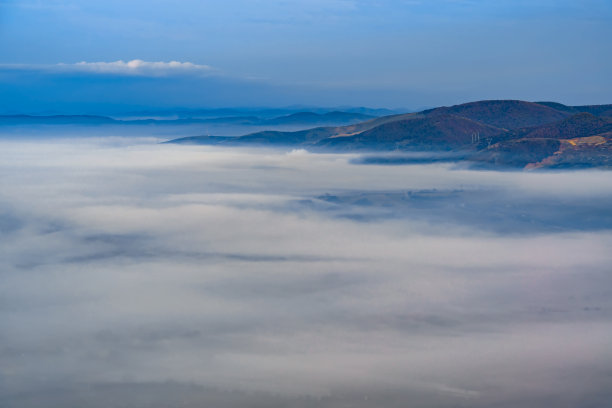 在清晨的薄雾中鸟瞰高地上的小镇是美丽的。低低的云和雾覆盖沉睡的城市，照片在满月的光。黎明时分，阿尔卑斯山脉山谷雾气蒙蒙图片下载