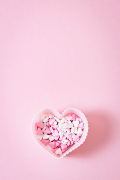 一种形式的松饼心形与糖果洒在粉红色的背景。图片下载