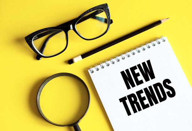 用眼镜、放大镜和铅笔在笔记本上写新趋势的课文。主要的趋势是改变一些东西。流行和趋势话题。商业新趋势。最新和最新的趋势。图片下载