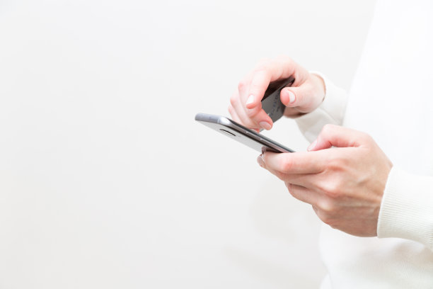 白色背景下女性手持信用卡和使用智能手机的特写镜头。女性在网上安全支付，使用银行服务，在网上商店订购。网上购物图片下载