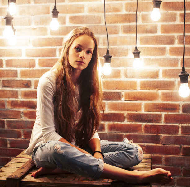 年轻的十几岁的女孩摆出欢快的姿势在现代阁楼工作室室内与许多灯，生活方式度假的人的概念图片下载