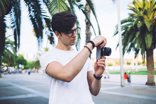 熟练的专业男性摄影师，专注于拍摄夏季周末城市广场的照片，沉思的男性游客在度假时拍摄地点和目的地图片下载