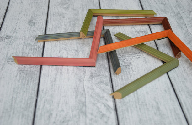 装饰木制相框样品。多色框架法棍，随机躺在一个木制的灯光背景。制定车间的概念。图片下载