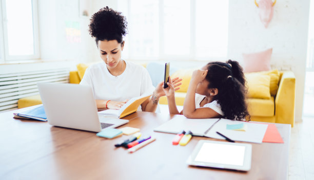 母亲在笔记本上查看笔记，女儿用手机拍照图片下载