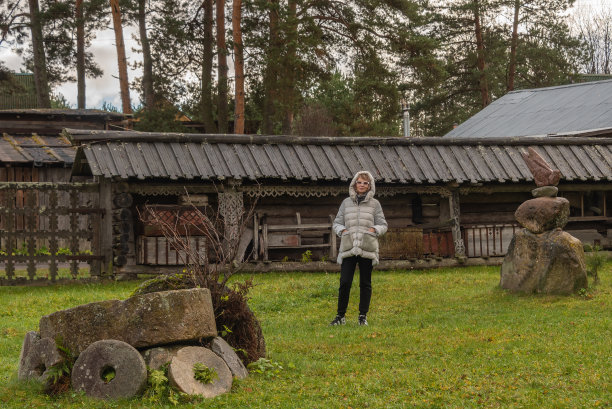 一个成熟的女人站在一个古老的乡村庭院的草坪上。图片下载