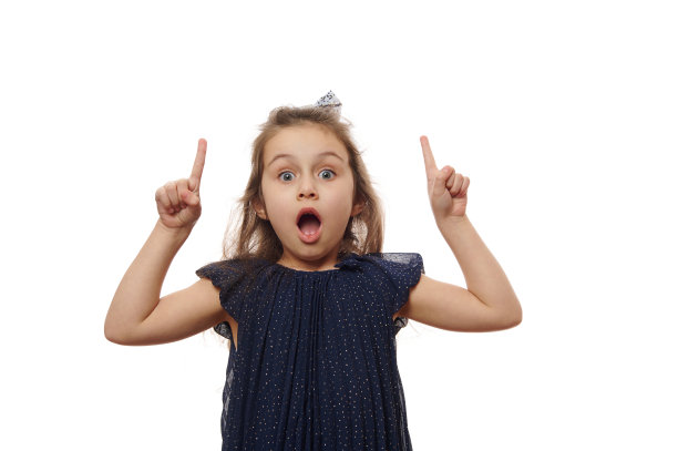 漂亮可爱的女婴，穿着优雅的海军蓝连衣裙，食指向上，寻找解决方案，在白色上张着嘴摆姿势图片下载