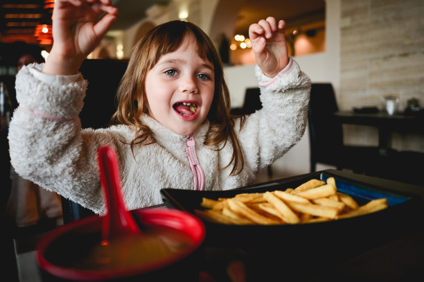 顽皮的女孩很高兴在餐厅。图片下载