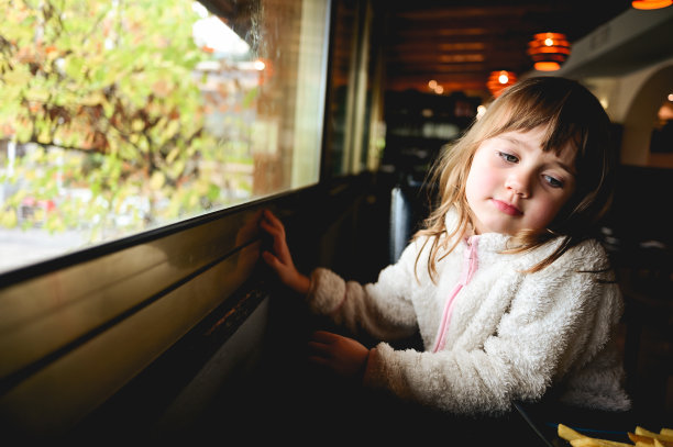 悲伤的小女孩坐在窗边。图片下载