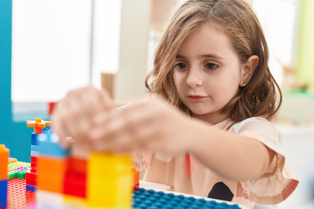 可爱的西班牙女孩坐在幼儿园的桌子上玩积木图片下载