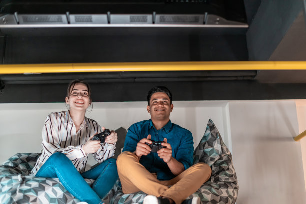 努力工作，尽情玩乐：创意创业办公室休息区，男女工人在休息时玩电脑游戏图片下载