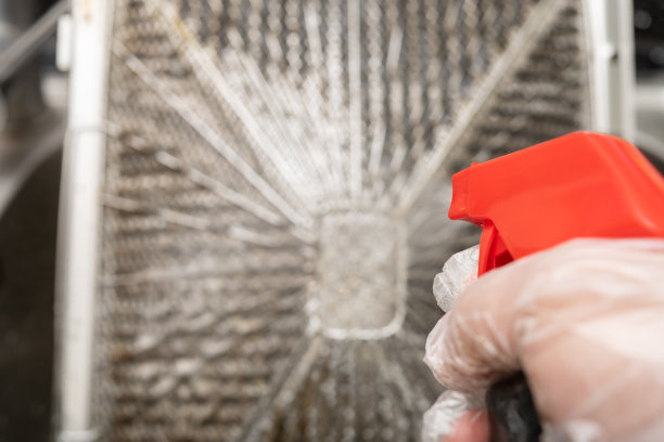 一名男子以水平组合向厨房通风机的油性过滤罩喷洒化学液体图片下载