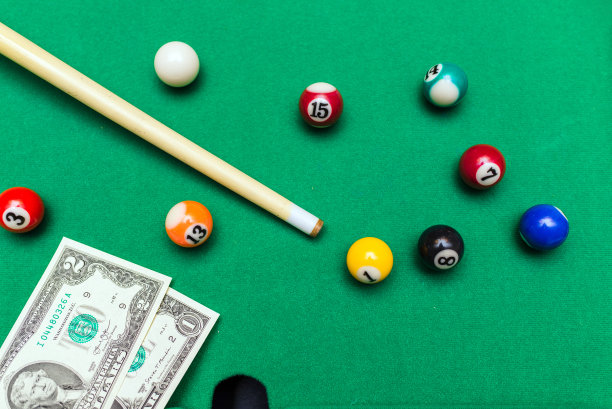 赌博狂热的游戏。钱和印有数字的彩色台球。游戏桌上有美元纸币。有选择性的重点。前视图。图片下载