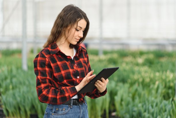 美丽的年轻微笑的女孩，工人花在温室。温室里的概念作品，花，郁金香，盒子里的花。副本的空间。图片下载
