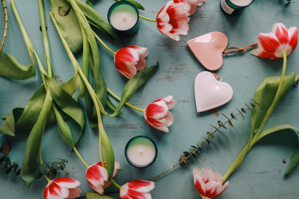 木桌上放着红色郁金香、爱心和蜡烛。情人节、母亲节、妇女节、婚礼或生日平铺概念。前视图。图片下载