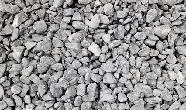 背景是一堆碎石的特写。用于外部地板覆盖物的粗糙鹅卵石用作背景。花园小径小石头堆松散装饰。图片下载