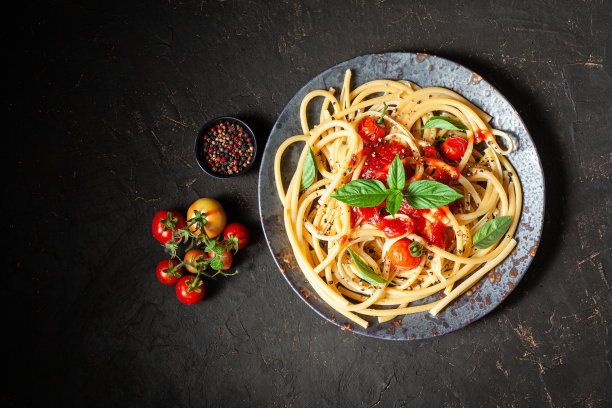 意大利面，黑碗的番茄酱意大利面。灰色的石头背景。，黑色背景。前视图。图片下载