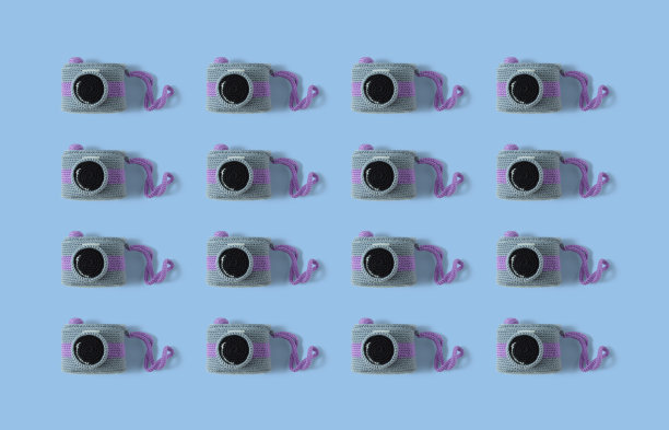 用彩色羊毛编织的复古相机图案。手工钩针相机在蓝色背景。复古相机的组成。Amigurumi相机图片下载