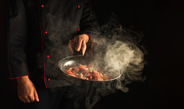 专业厨师在煎锅里准备蔬菜。在深色背景上烹饪健康的素食食物和餐点。免费广告位图片下载