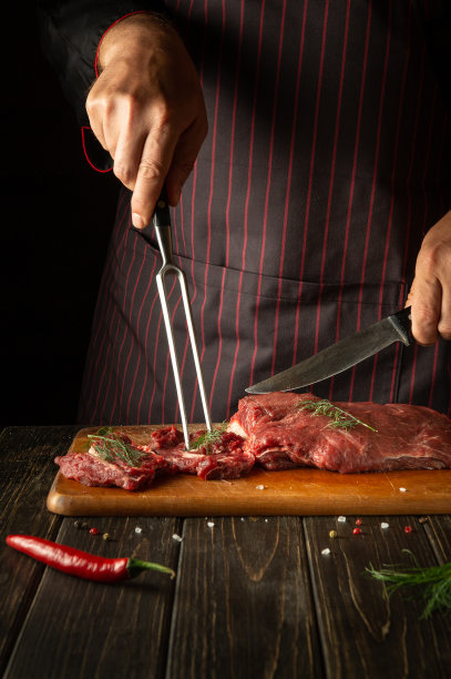 一个有经验的厨师准备生的新鲜牛肉烘烤或烧烤。餐厅或酒店厨房的工作环境。图片下载