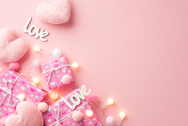 情人节的概念。礼盒的顶部视图照片蓬松的心形玩具铭文爱灯泡花环和软绒球在孤立的粉彩粉红色背景与复制空间图片下载