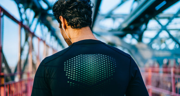 肌肉健美运动员听音乐播放列表在娱乐与体育活动在城市城市，运动员享受健康的生活方式站在户外，享受播客的背影图片下载